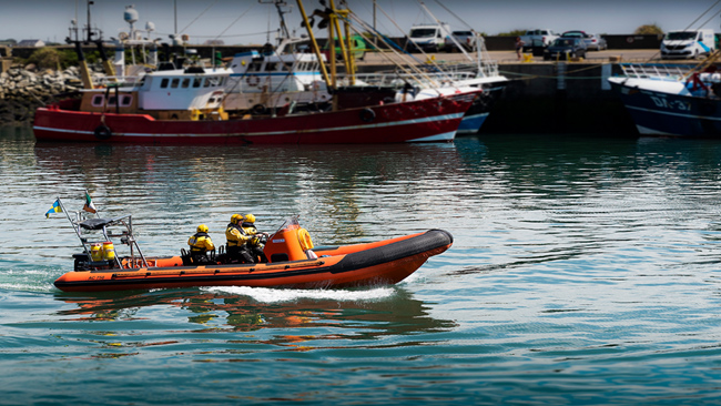 SFPA rigid inflatable boat cruising in sea port with trawlers in background